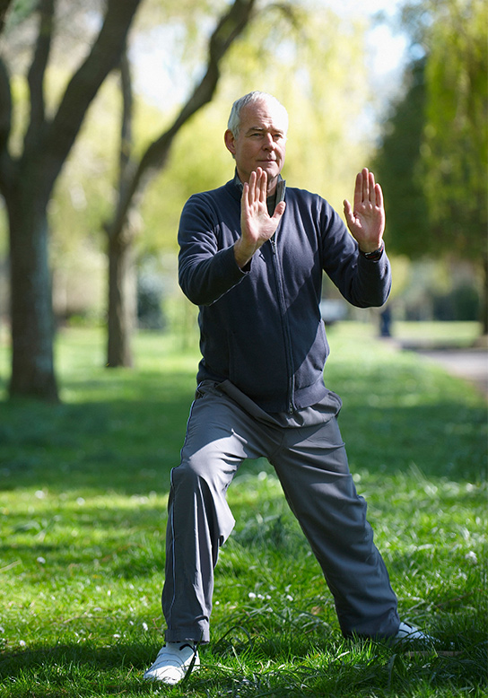 older man outside doing yoga